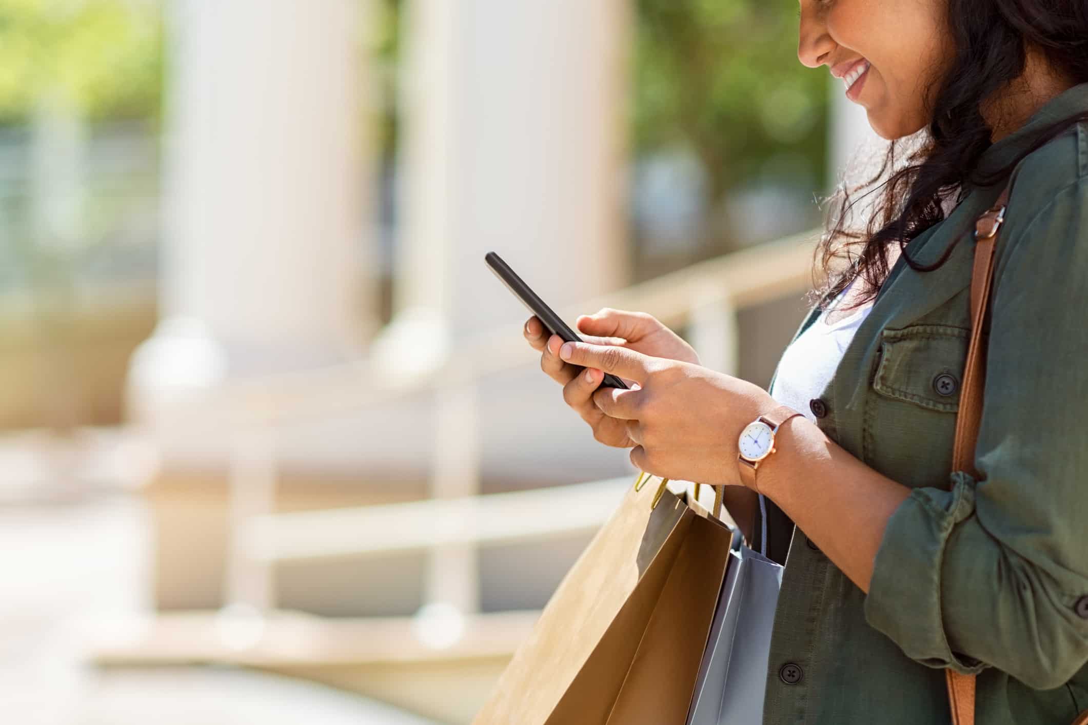 Woman with shopping bags using phone StatSocial Consumer Data